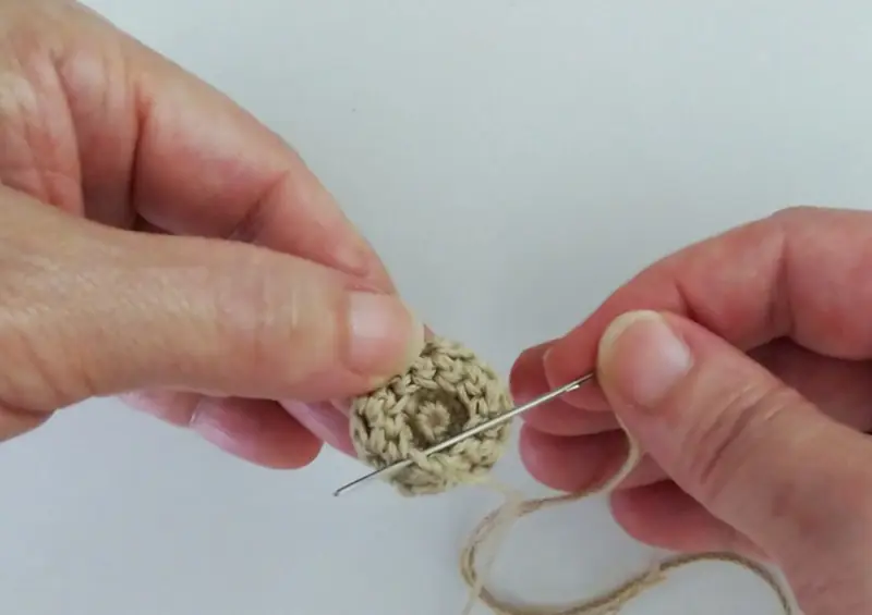 帽子の編み終わりの最後の細編みの目にとじ針を通しているところ